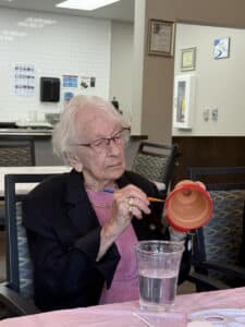A memory care resident at Meadowview of Davenport focuses on painting a flowerpot during a creative activity.