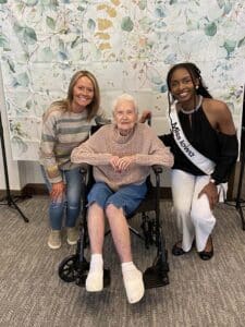A Meadowview of Davenport memory care resident smiles with Miss Iowa and a team member during a special visit.